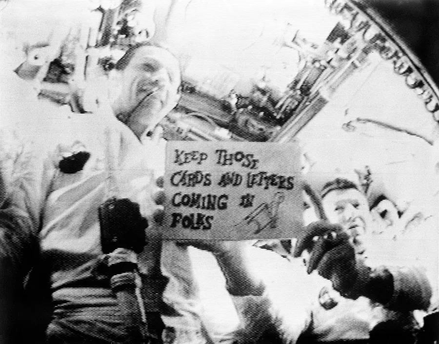 An Apollo 7 crewman holds up one of the handwritten cue cards used in the first live television broadcast from an American spacecraft.