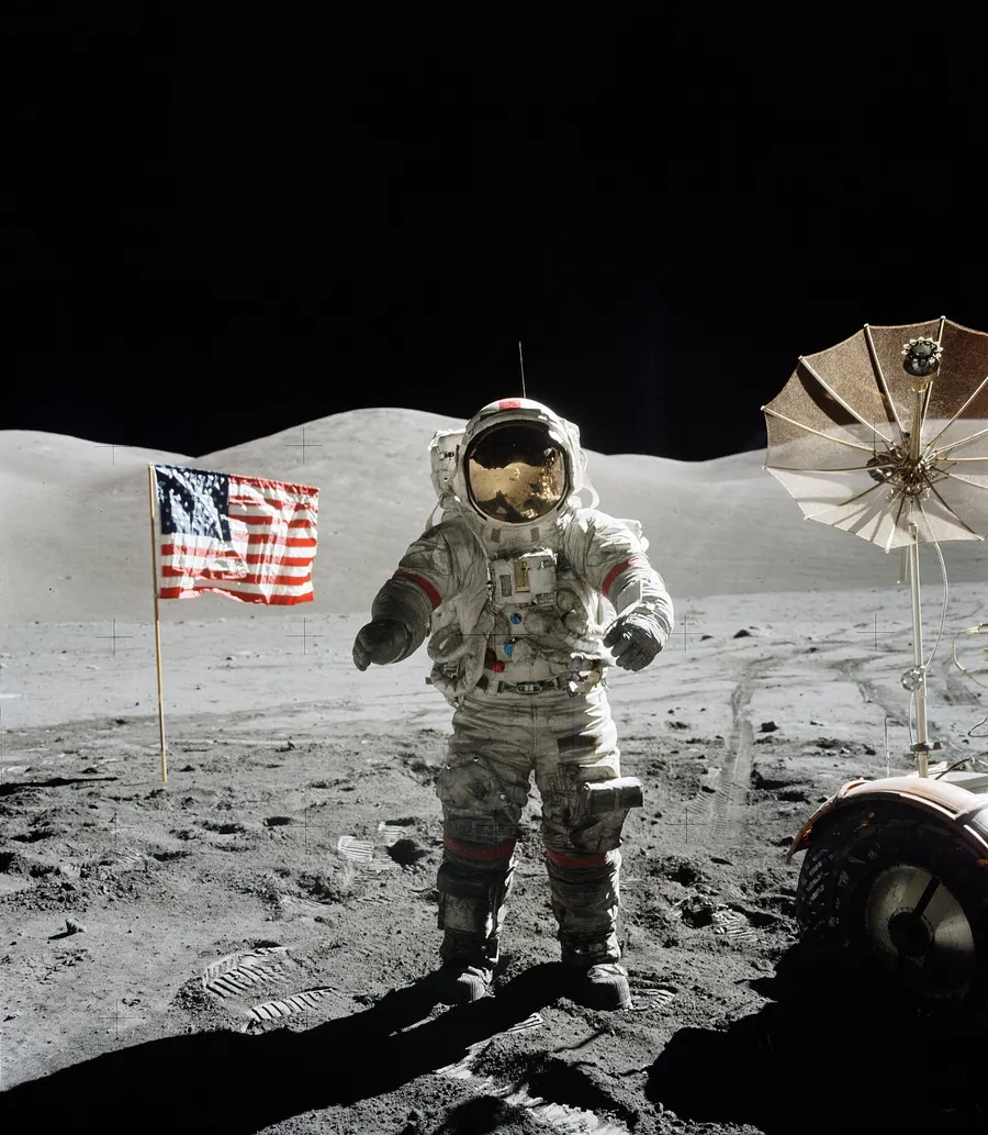 Eugene Cernan beside the flag at the Taurus-Littrow landing site, with the lunar rover behind him.