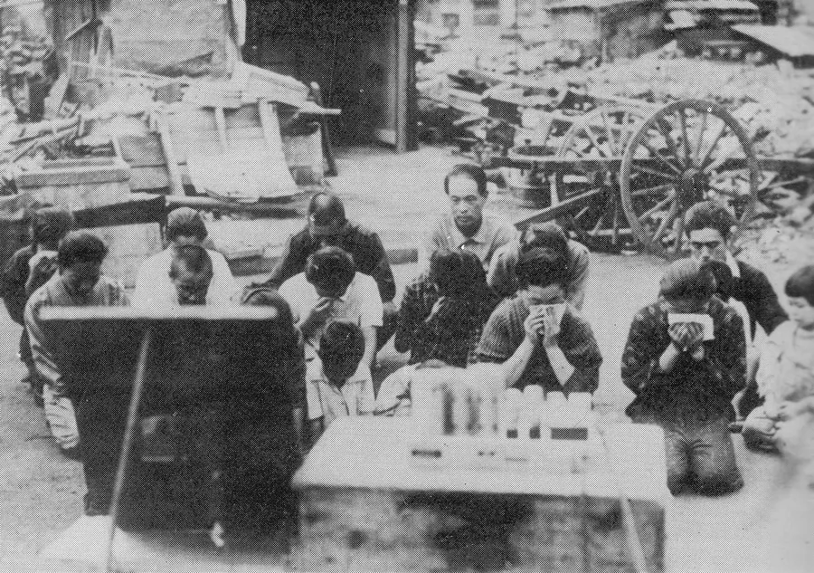Japanese civilians bow their heads as they listen to the emperor's broadcast on 15 August 1945