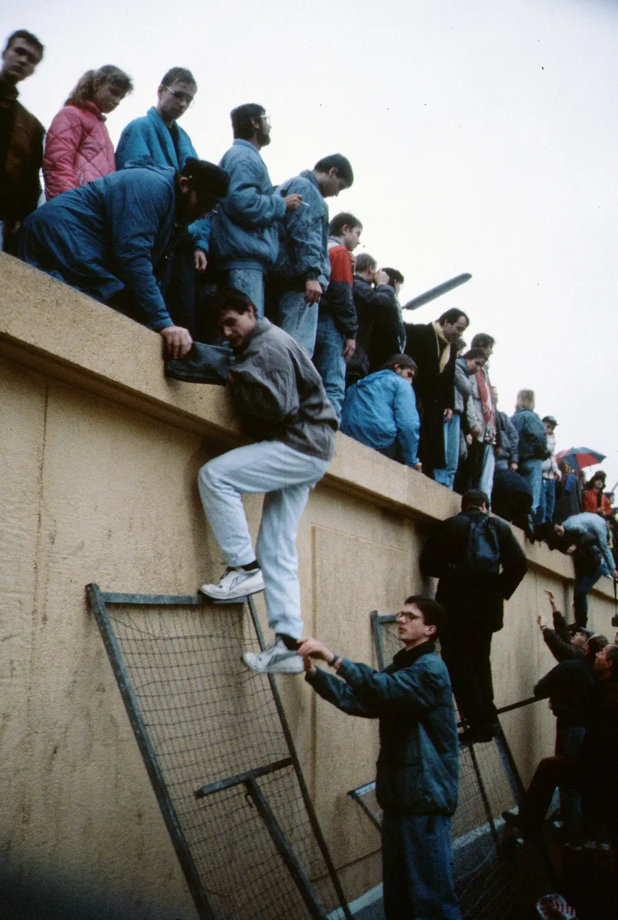 People climb on to the Berlin Wall as it opens, November 1989.