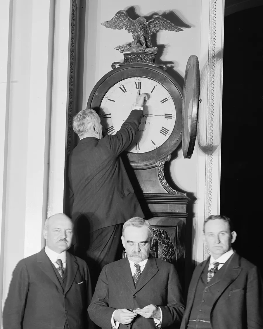 The Senate's Sergeant at Arms turns the Ohio Clock forward for the first daylight saving time, watched by three senators, 1918.