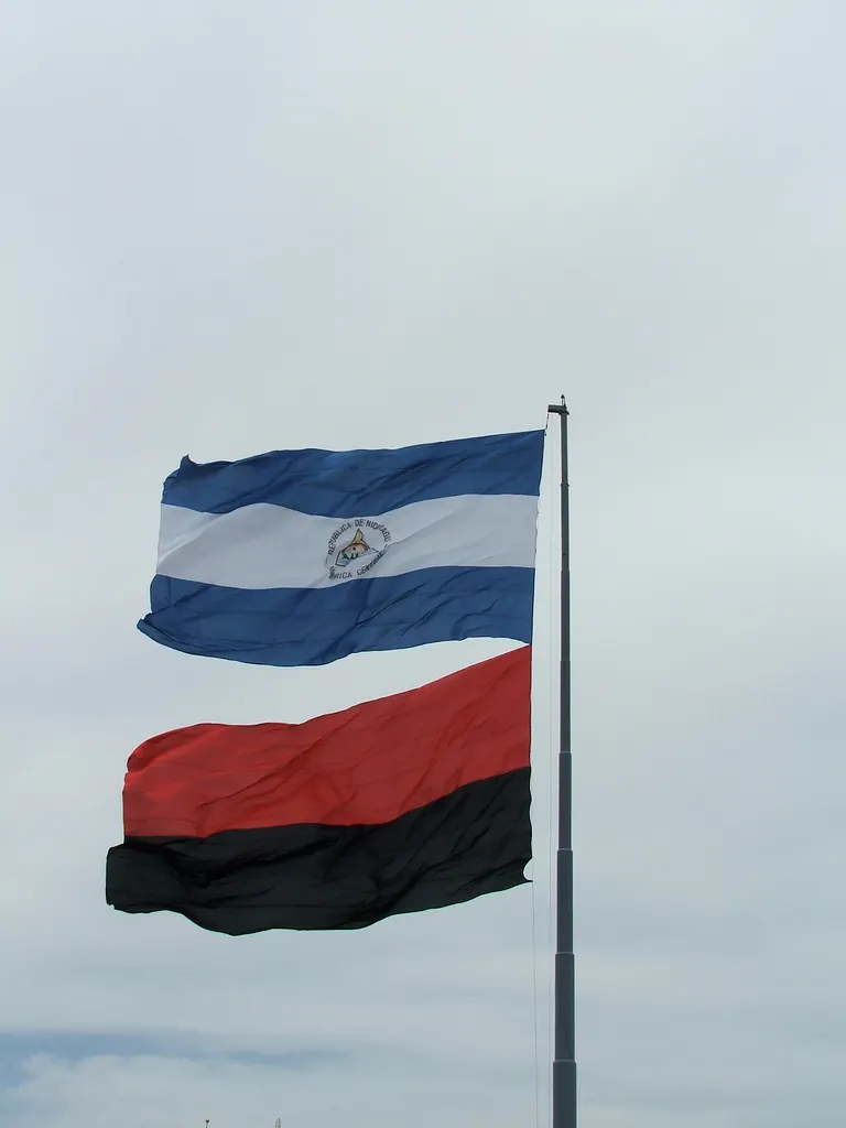 The blue and white flag of Nicaragua beside the red and black flag of the Sandinista Front