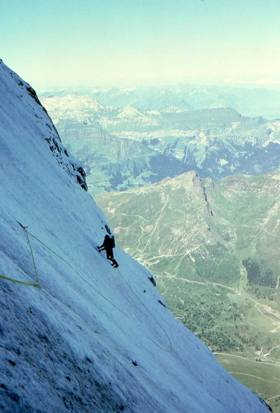 A climber on the steep ice of the Eiger north face, high above the valley