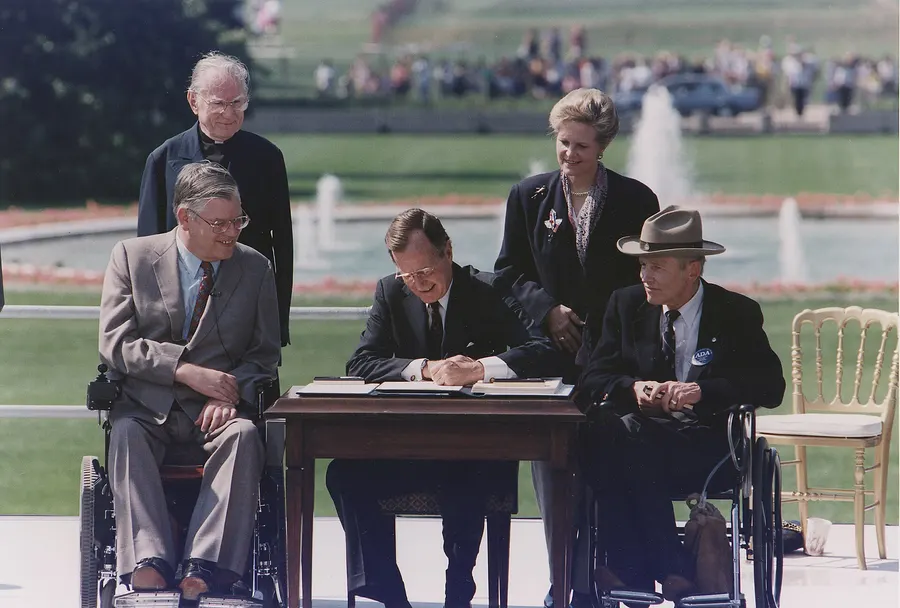 President George H. W. Bush signs the Americans with Disabilities Act on the South Lawn of the White House, 26 July 1990