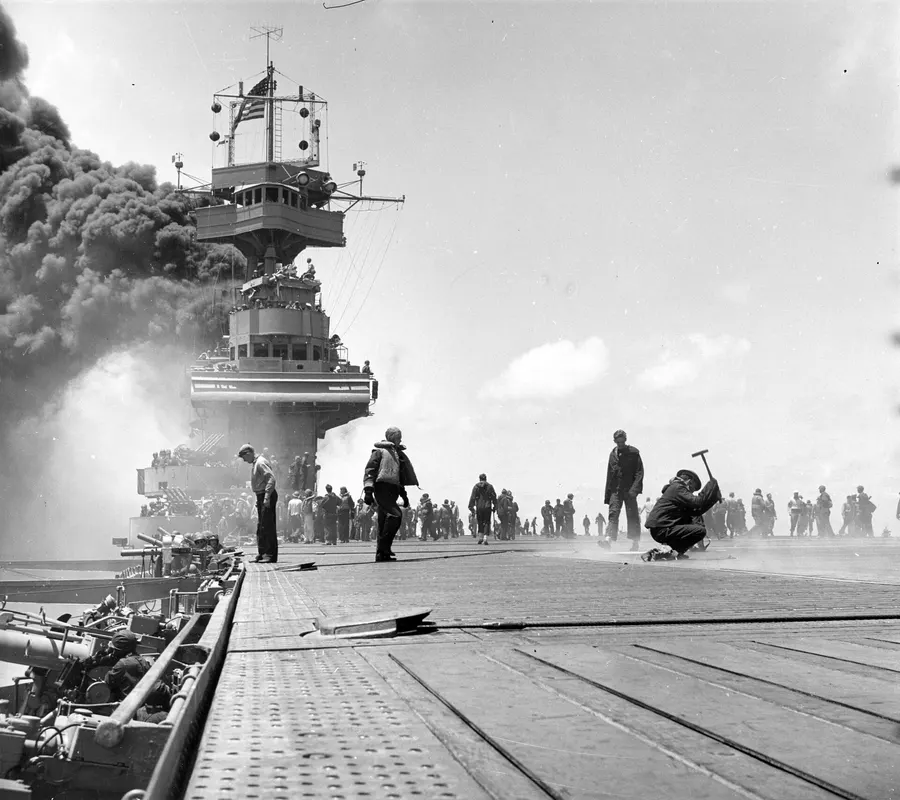 Crewmen on the smoke-covered flight deck of the carrier USS Yorktown after Japanese bombs struck her at Midway, June 1942
