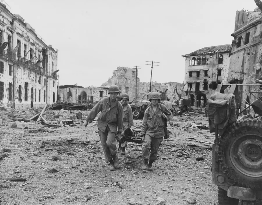 US soldiers carry a wounded man on a stretcher through wrecked buildings in Manila's walled city, 23 February 1945.
