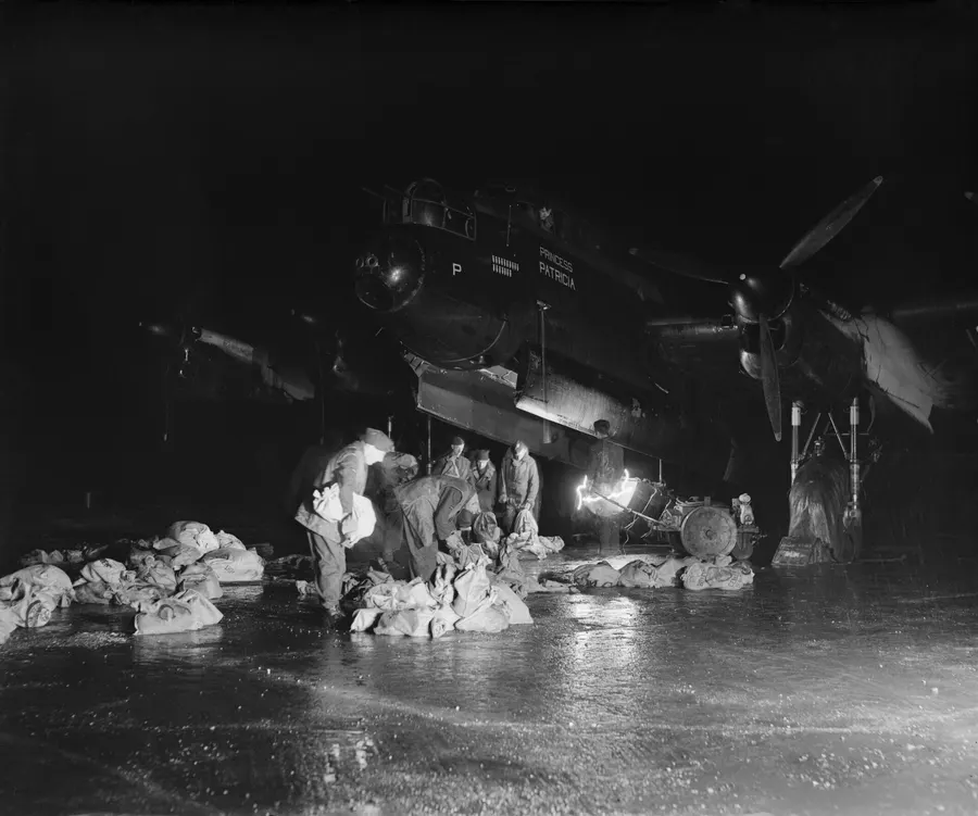 RAF ground crew at Waterbeach load food into a Lancaster's bomb bay for Operation Manna, 29 April 1945.