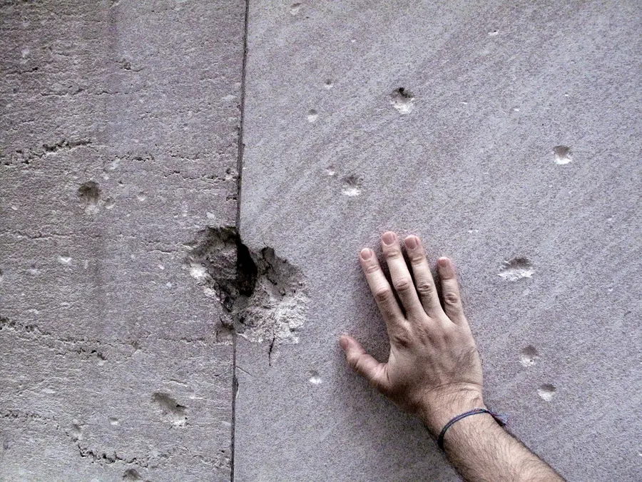 Marks left by the 1920 explosion, still visible in the stone wall of the former Morgan building on Wall Street; a hand shows their scale