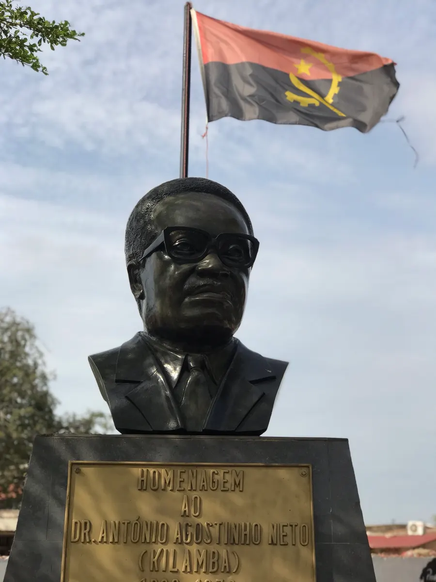 A bust of Agostinho Neto, the first president of Angola, beneath the Angolan flag