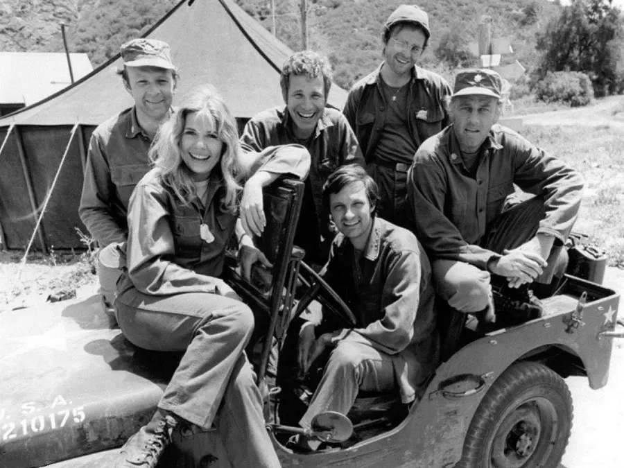 The cast of M*A*S*H in a CBS publicity photograph of 1974, with Alan Alda at the wheel of the jeep
