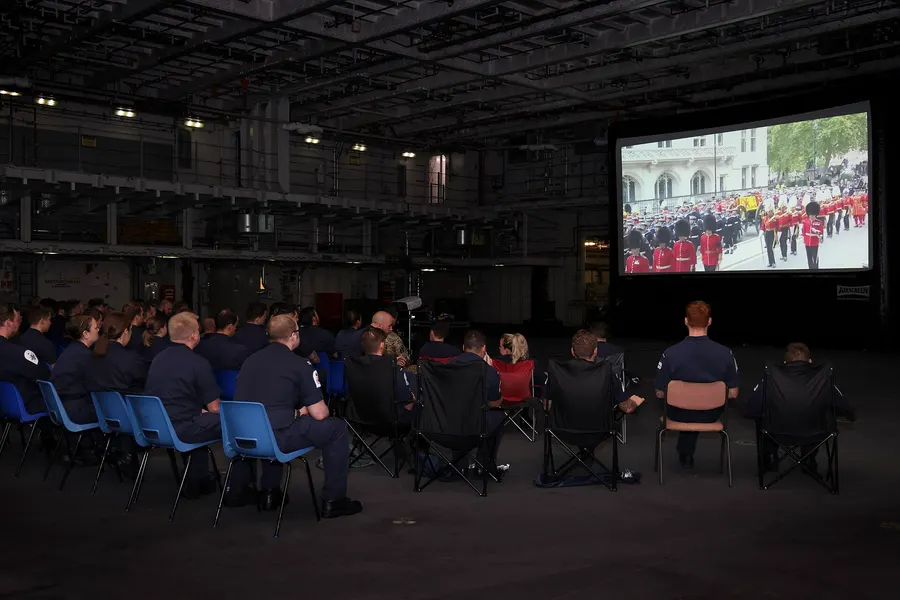 Sailors aboard HMS Queen Elizabeth watch the Queen's funeral on a big screen, 19 September 2022.