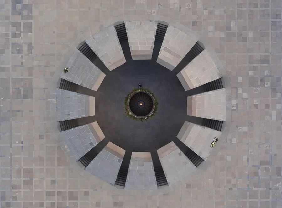 The eternal flame at Tsitsernakaberd, the Armenian genocide memorial in Yerevan, seen from above as a visitor lays flowers.