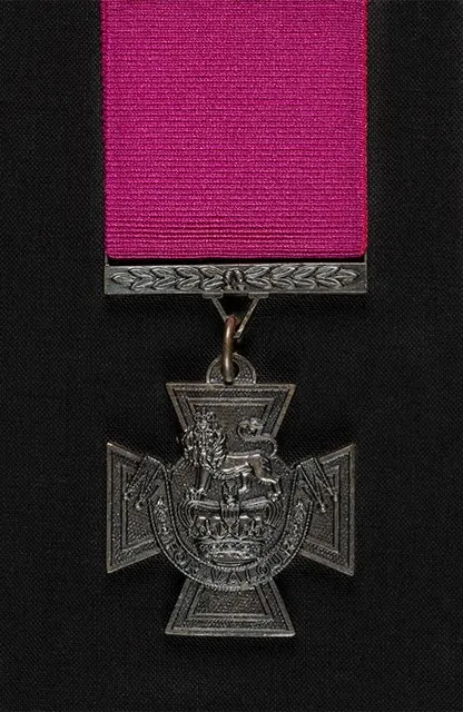 The Victoria Cross, with the inscription 'For Valour' and its crimson ribbon.